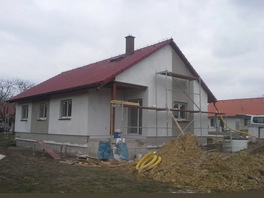 Průčelí domu s&nbsp;červenou střechou a&nbsp;lešením, Nové Dvory