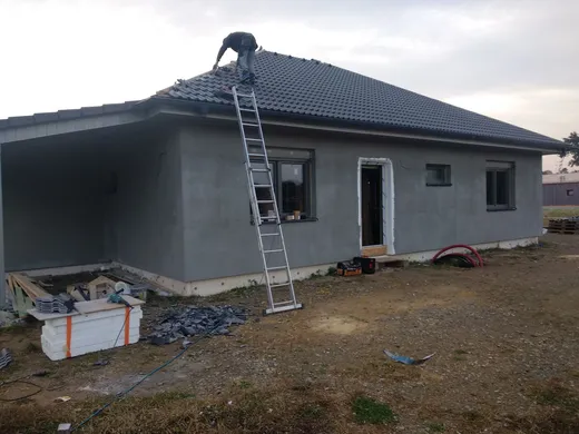 Dokončování fasády v&nbsp;šedé omítce a&nbsp;pokládka tmavé střešní krytiny